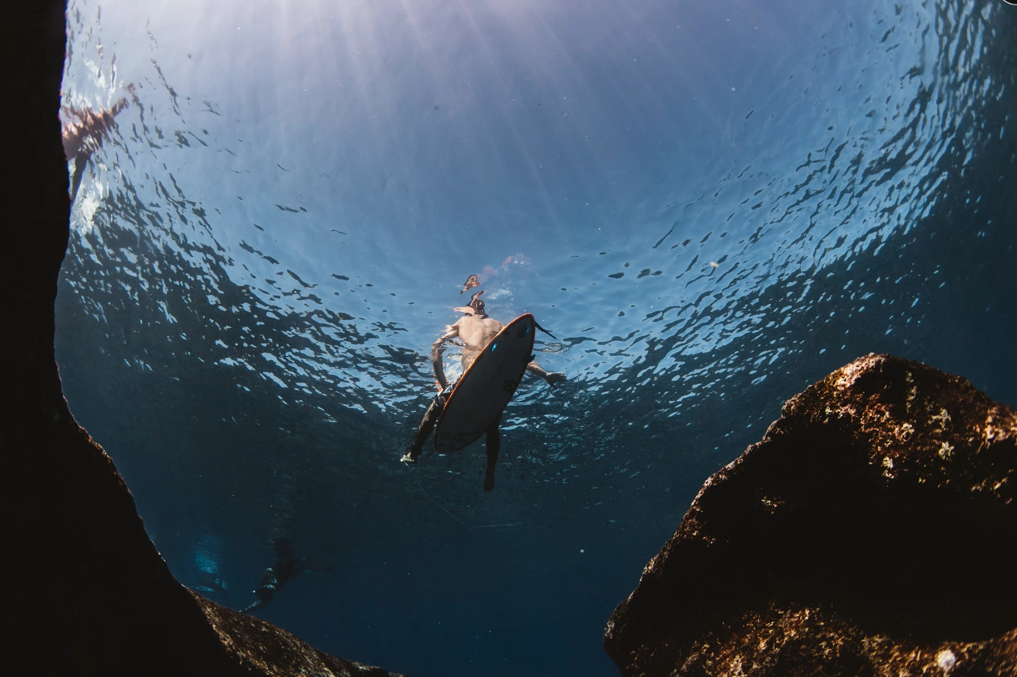 Looking up through blue water as a surfer passes overhead