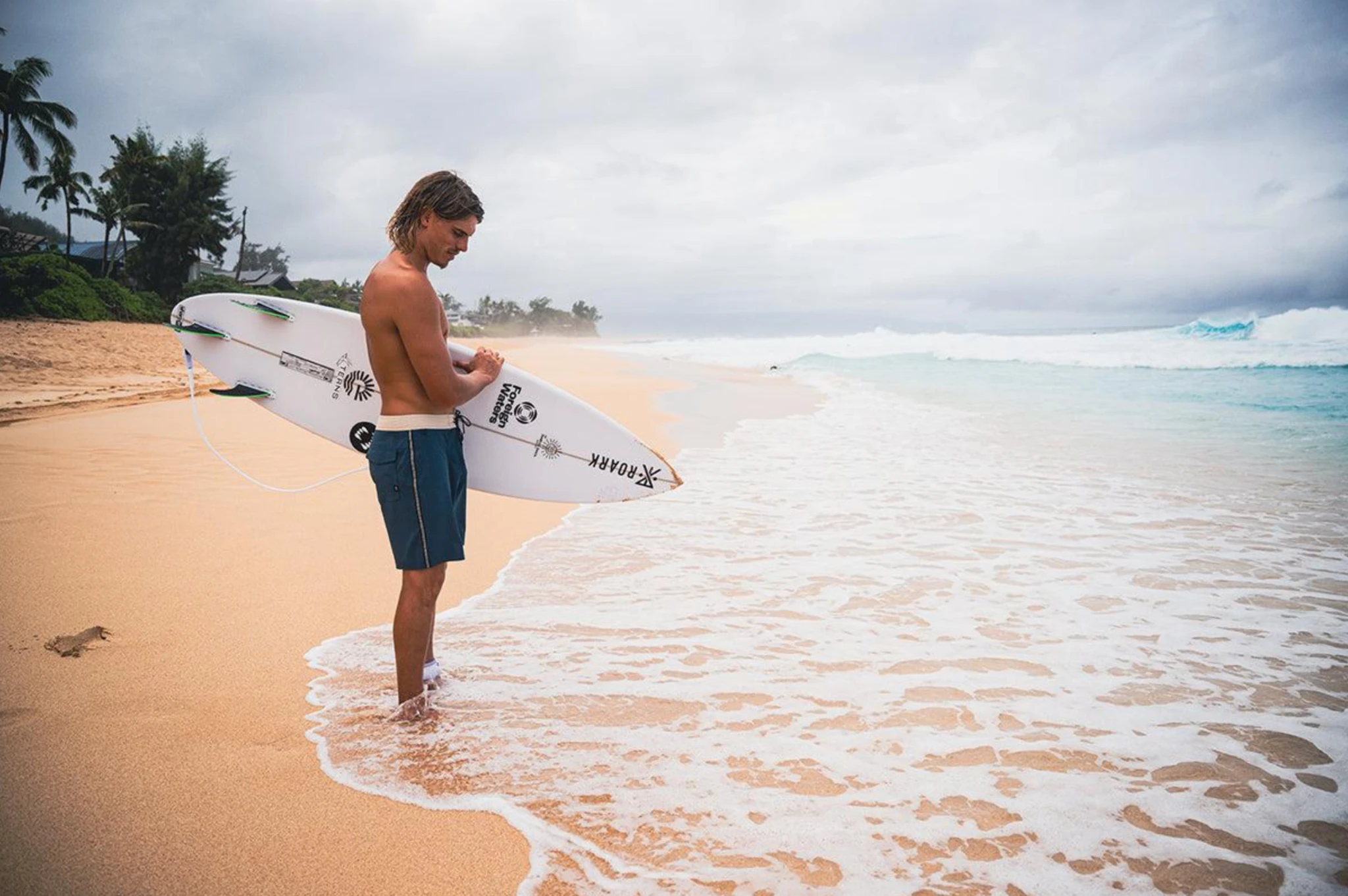 A surfer preparing a board at the shoreline