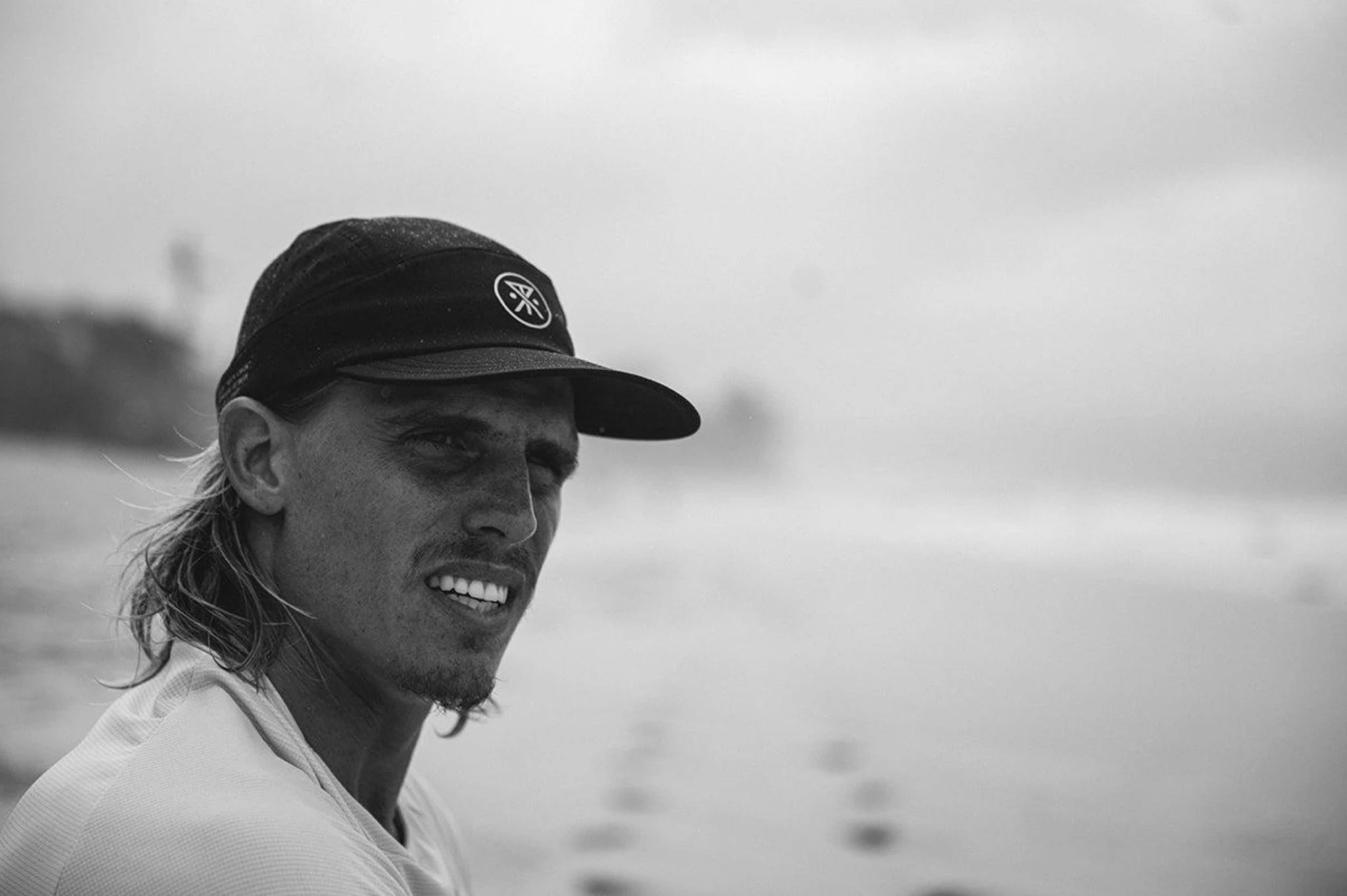 Koa Smith wearing a cap, looking toward the water