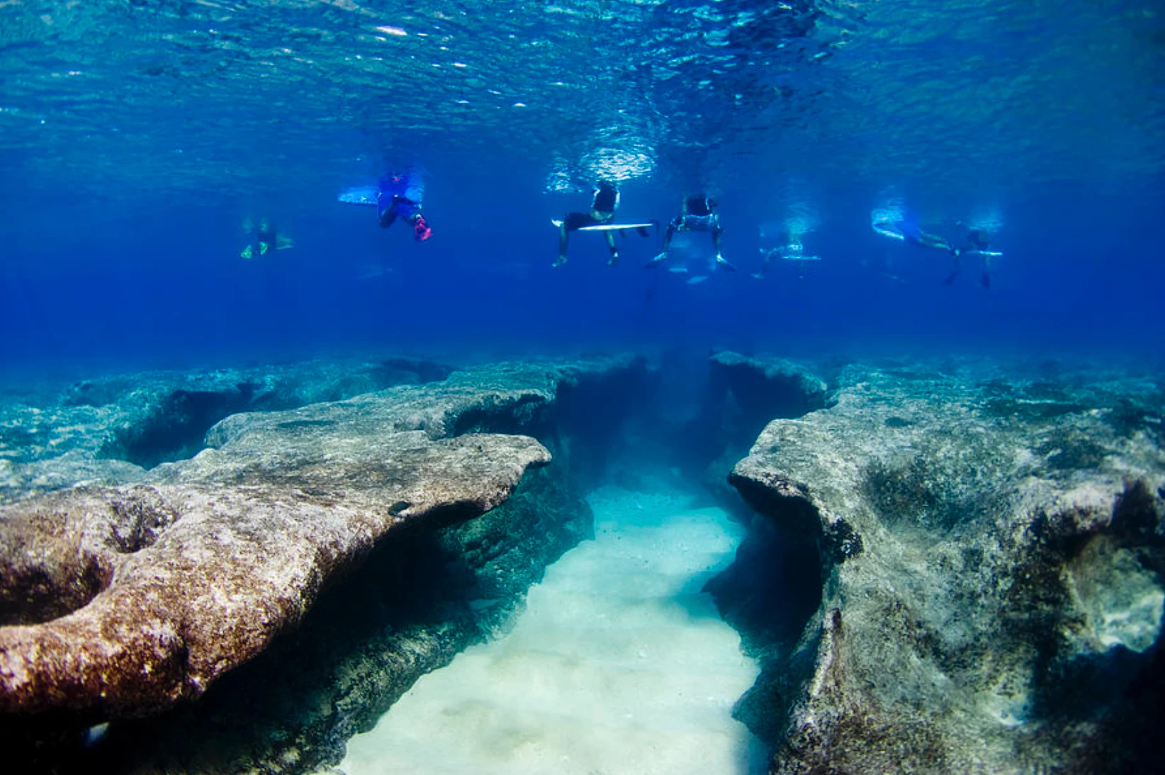 Underwater reef ledges with surfers waiting at the surface above